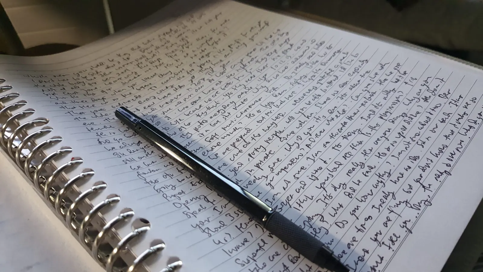手書きの文字で埋まったノートとペン